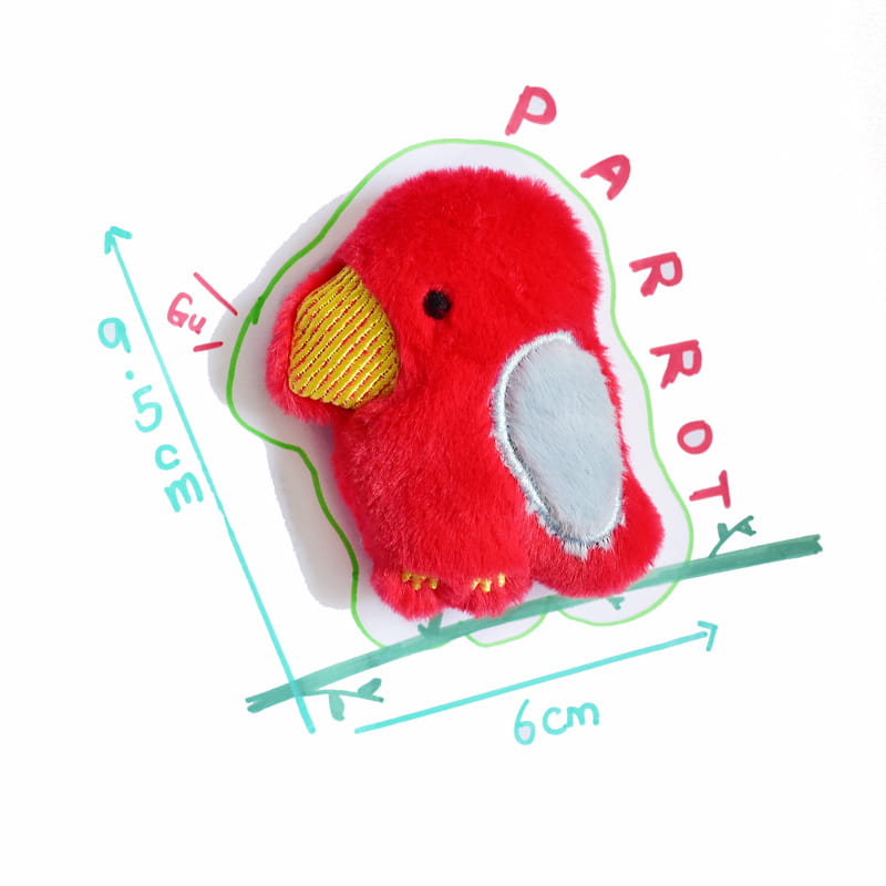 黄色いくちばしとグレーの翼、そして刺繍のディテールが特徴の、レッドのオウムのぬいぐるみです。インタラクティブな笛（スウィーカー）付きのぬいぐるみ犬用おもちゃとしてデザインされています。