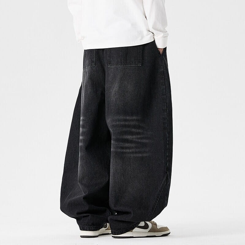 Des jeans japonais rétro à jambes larges pour hommes en grandes tailles en denim noir, avec une coupe ample et décontractée et un aspect vieilli subtil avec des marques d’usure.