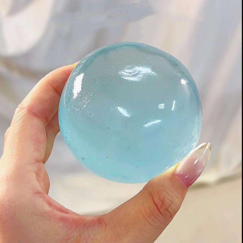 Eine transluzente hellblaue Gel-Kugel aus TPR-Material, mit Kokosöl angereichert, in der Hand gehalten als Fidget-Spielzeug zur Stresslinderung.