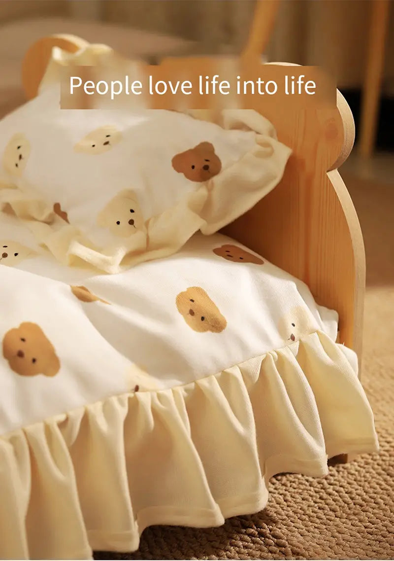 Cream-colored ruffled bedspread with tan bear faces on a wooden cat bed featuring a playful bear pattern.