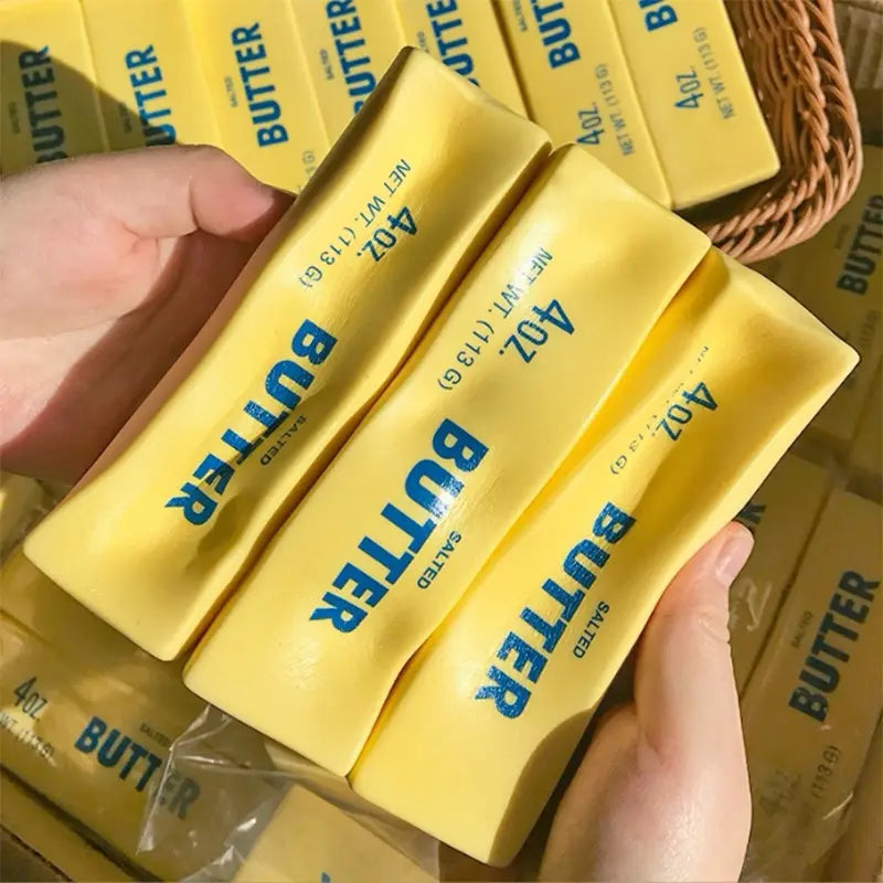 yellow salted butter sticks labeled butter in blue text with a net weight of 4 oz from the slow rising butter stick stress relief toy product.