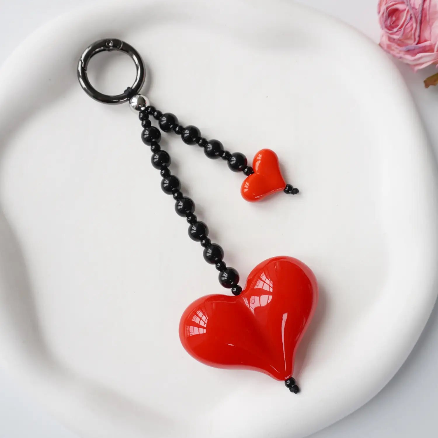 Porte-clés en forme de cœur rouge, pendentif pour sac à perles, avec une finition brillante et un pendentif plus grand et un pendentif plus petit reliés par des perles noires.