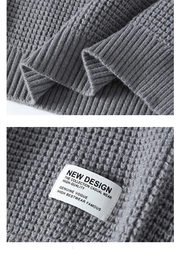 Grauer gerippter Strick-Pullover von Moownuc für Herren im Waffelstrick-Look mit strukturiertem Waffelstrick-Muster und weißem Label, das ein neues Design sowie echte Vogue anzeigt.