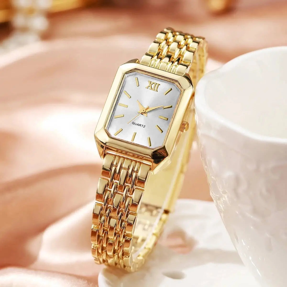 Women gold rectangle quartz watch with a silver dial featuring roman numeral hour markers and an interlocking metal mesh strap design.