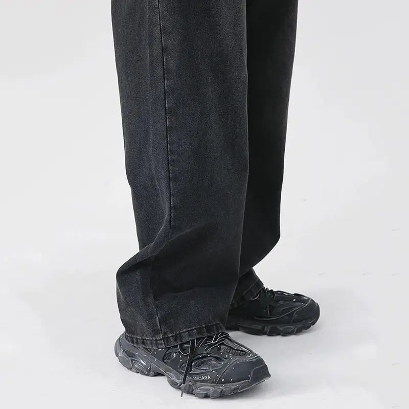 Herren schwarze Wide-Leg-Denim-Jeans, kombiniert mit schwarzen Balenciaga Triple-S-Sneakers mit klobiger Gummisohle und gesprenkelter Textur