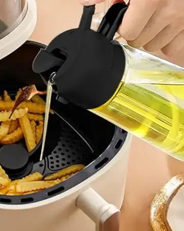 un vaporisateur d’huile en verre transparent de 500 ml avec bec et poignée en plastique noir, rempli d’une huile de cuisine jaune doré pour une utilisation en cuisson