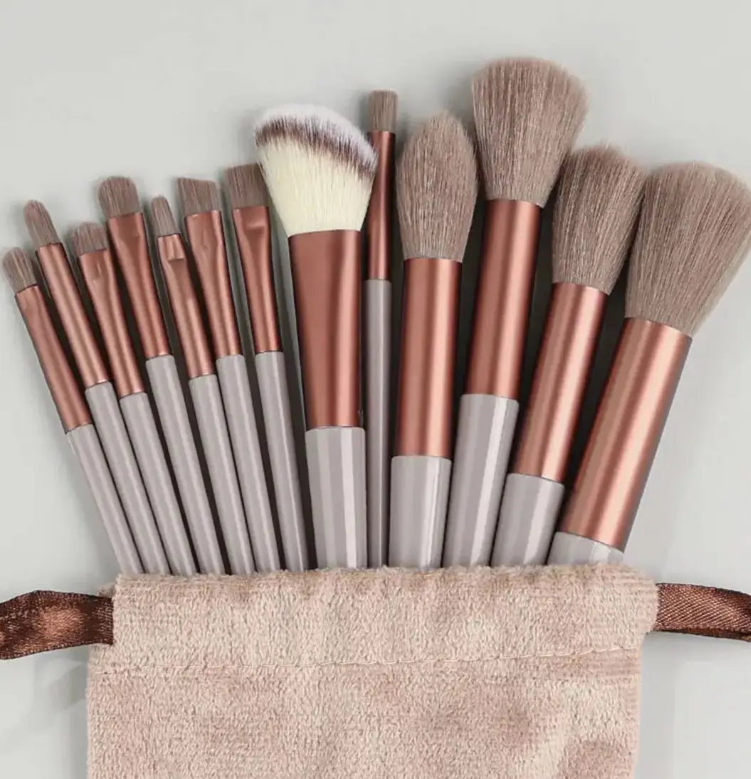 Un ensemble de 12 pinceaux de maquillage en or rosé et gris avec des poils en nylon souples, disposés dans une pochette en tissu de couleur blush à partir de l’ensemble de pinceaux et d’éponges de maquillage de 33 pièces, avec des poils en nylon mettant en évidence la qualité de la matière des pinceaux.