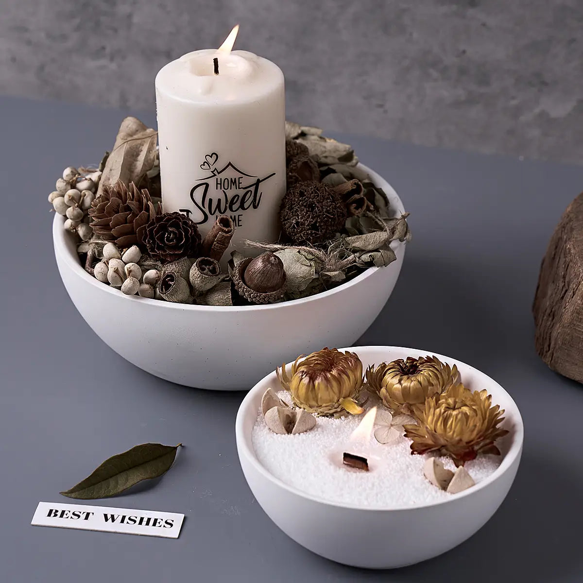 white candle with home sweet home inscription in black script surrounded by dried botanicals nestled within a white ceramic bowl made using a round silicone mold for concrete storage bowls and candles