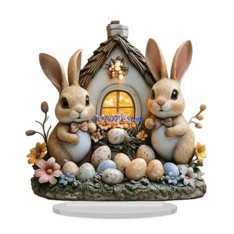 tiernas estatuillas de conejito de Pascua de acrílico color beige y blanco con lazos que custodian una casita en miniatura, rodeada de huevos de Pascua en colores pastel y flores, como centro de mesa primaveral.