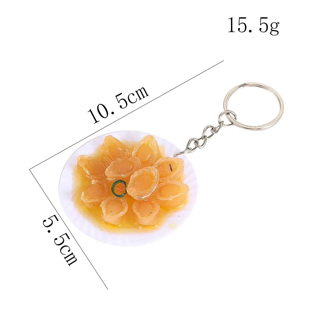 Miniature food keychain featuring a detailed translucent orange resin replica of a scallop dish arranged on a white plate.