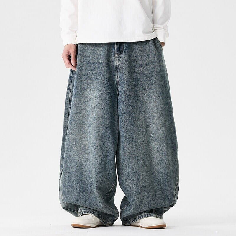 Des jeans japonais rétro à jambes larges pour hommes en grandes tailles en denim bleu délavé, avec une coupe ample et décontractée et des détails de surpiqûres visibles.
