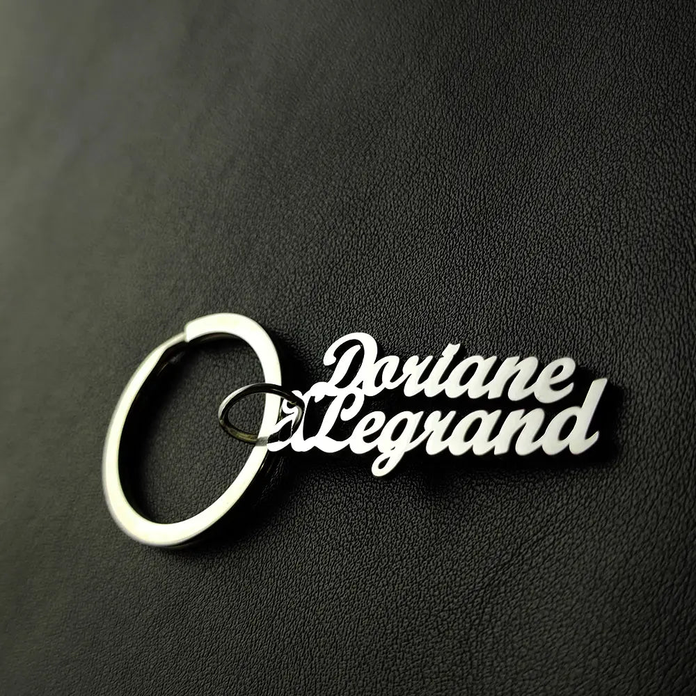 Llavero de nombre personalizado de metal plateado, hecho de joyería de acero inoxidable, con el nombre «doriane d legrand» en una caligrafía cursiva elegante.