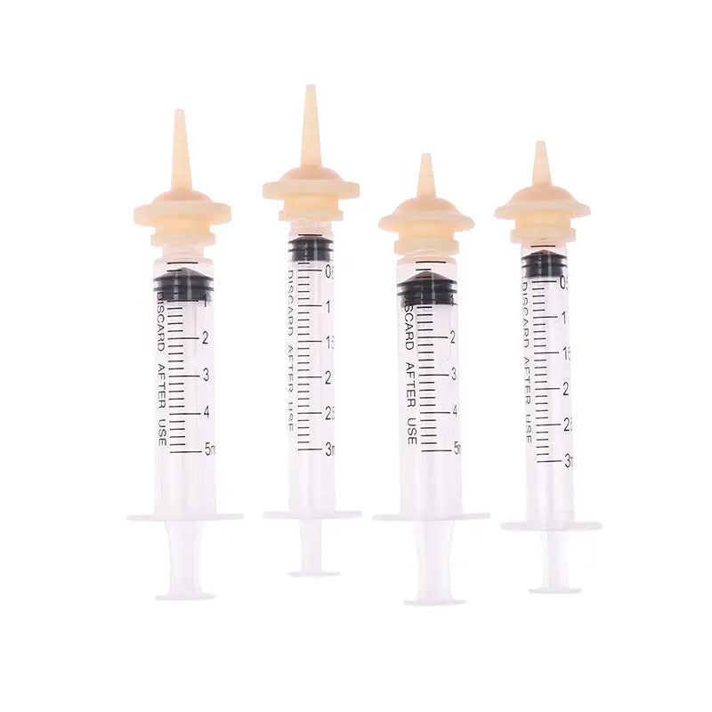 Four transparent plastic pet oral syringes with beige caps and black plunger seals marked with measurement scales included in a feeding set with silicone nipples.