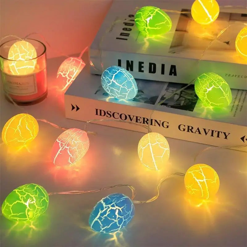 Bunte, gesprünkelte LED-Lichterketten in Form von knalligen Eiern, gelb, grün und blau, zusammen mit einem Set von 35 cm Osterhasen-Figuren aus Stroh zur festlichen Dekoration.