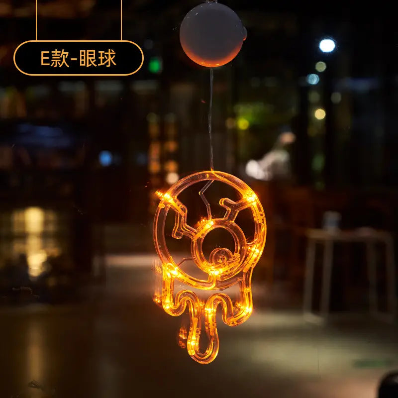 A glowing orange LED light-up skull-shaped car hanging ornament with a spherical top designed as a battery-operated Halloween window light decor.