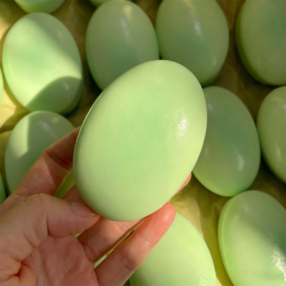 Un juguete esponjoso y blando para aliviar el estrés, de superficie lisa y brillante, de color verde pálido, con forma de huevo, lento en elevarse, con apariencia de pastel de queso.