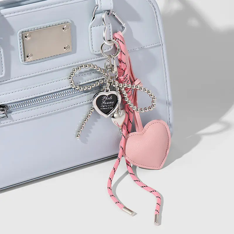 Heart pendant bowknot bag keychain featuring a pink heart-shaped leather charm with a silver beaded chain and a small engraved metal tag.