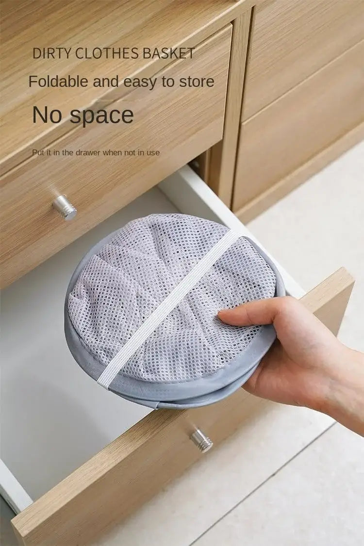 Panier de rangement pour linge pliable gris, fabriqué en maille, avec une sangle élastique blanche, conçu comme organisateur de panier à linge monté au mur.