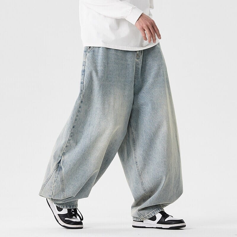 Des jeans japonais rétro à jambes larges pour hommes en grandes tailles en denim bleu clair, avec une coupe large et décontractée et des détails de surpiqûres visibles.