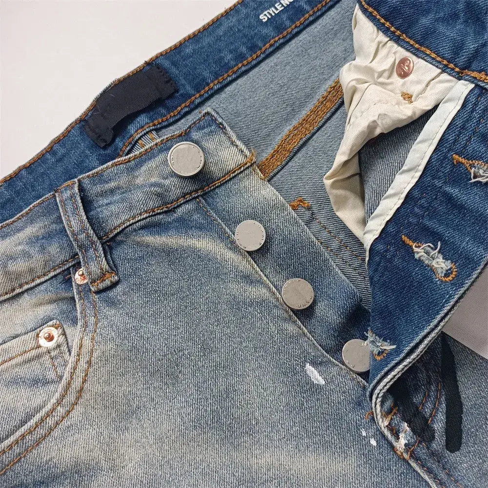 Jeans skinny déchirés pour hommes en denim bleu, présentant des détails déchirés et des boutons ton argent.