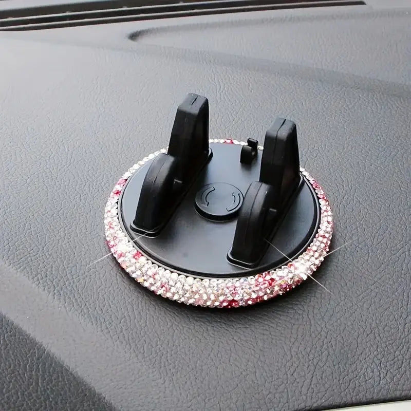 Un soporte circular negro para teléfono de automóvil con ventilación, con ribete brillante en rosa y transparente.