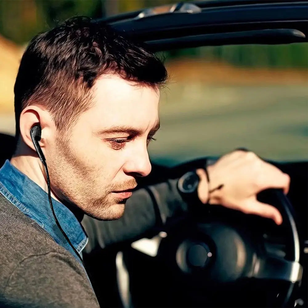 Un homme portant des écouteurs filaires noirs de 5 mm avec un fil fin dans son oreille en conduisant, conçus pour les appareils mp3 mp4.