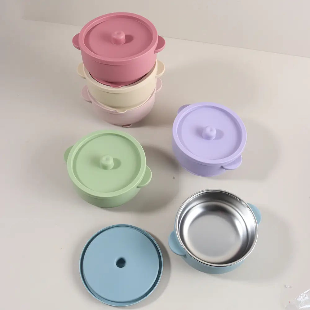 Pastellfarbene Baby-Trainingsschüsseln mit Edelstahlinnenbereich, Silikondeckeln und weichen Griffen, konzipiert für das Zufüttern und Babynahrung.