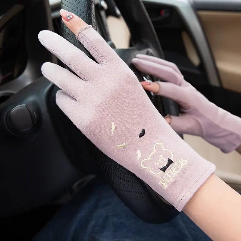Himbeerrosa fingerlose Fahrhandschuhe aus atmungsaktivem Material mit UV-Schutz, mit einem niedlichen bestickten Bärenkopf und dem Burub-Markenname am Handgelenk, von der Rückseite abgebildet.