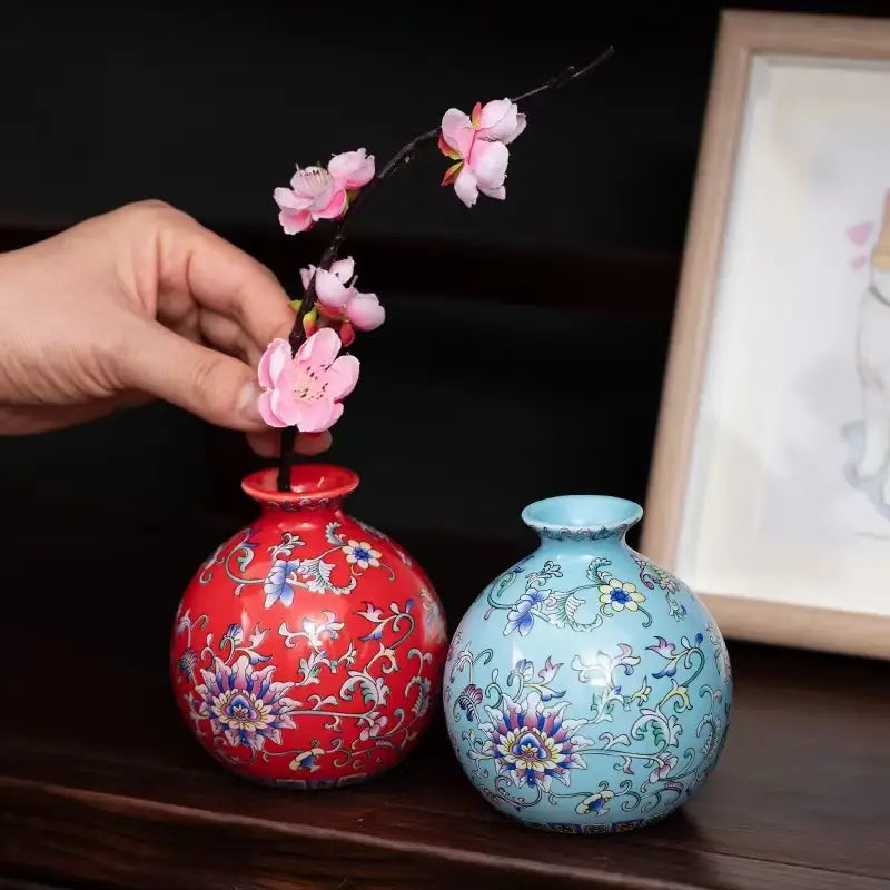 Une paire de deux petits vases en émail de céramique ronds, ornés et élaborés, de couleur rouge vif et bleu clair, présentant des motifs floraux de porcelaine chinoise d’inspiration ancienne