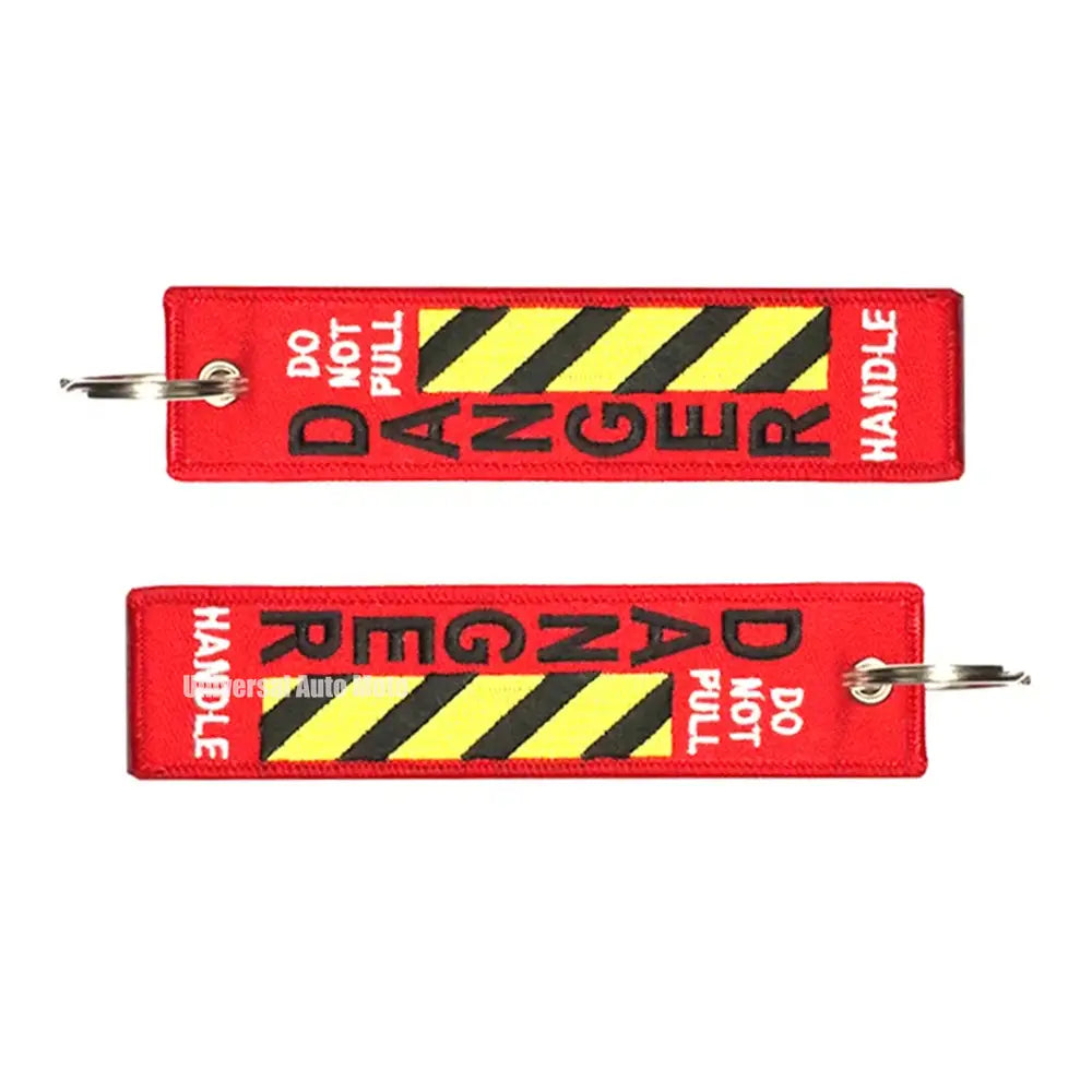 黒と黄色のハザードストライプをあしらった、JDMオートバイ用のキーホルダーとしてデザインされた「危険」警告の赤い刺繍キーホルダー。