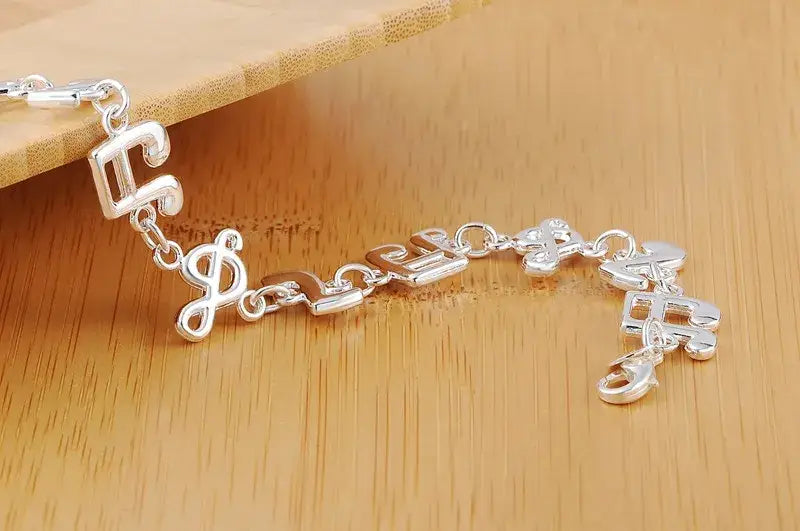 Silver musical note sterling silver bracelet featuring a polished silver dollar sign charm with interlocking links.