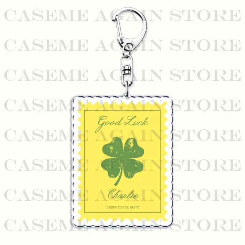 Yellow rectangular acrylic keychain with a green four-leaf clover design and good luck charlie text in black cursive, featuring a silver metal clasp, ideal as a gracie abrams anime fan gift.