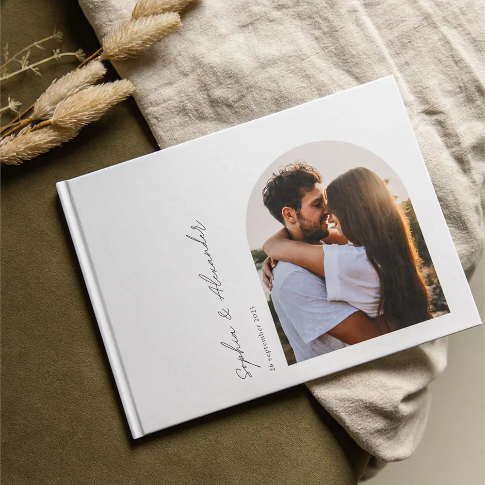 Individuelles Hardcover-Gästebuch für eine Hochzeit mit Foto in Weiß, mit einem runden Foto eines Paares in inniger Umarmung auf dem Einband, versehen mit eleganter Handschrift, Sophie und Alexander, sowie dem Datum 06. September 2023.