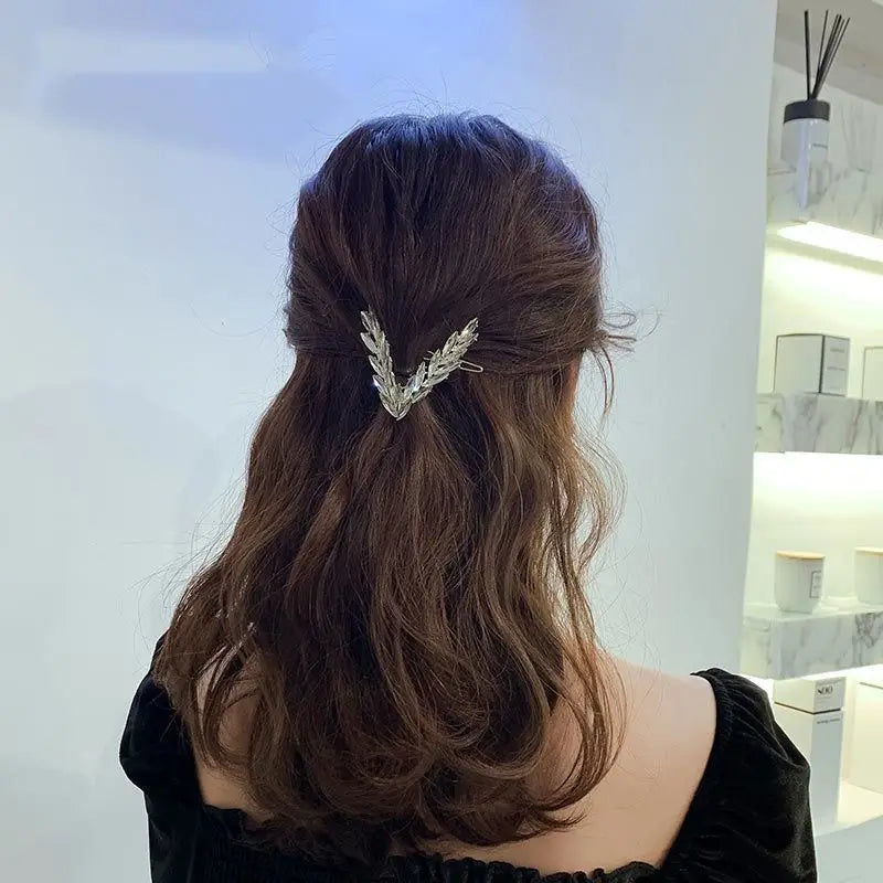 Silver leaf-shaped hair clip from the crystal v shape hair clip set holding back dark brown wavy hair.