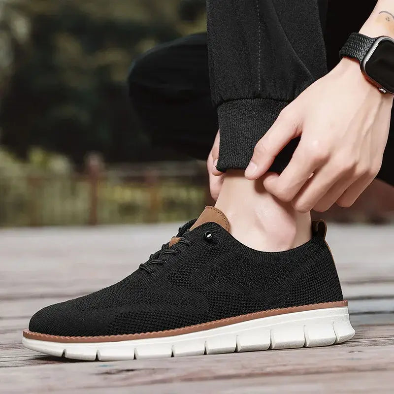 Chaussure derby brogue décontractée en maille pour hommes, noire, avec des accents en cuir marron et une semelle en caoutchouc blanc.