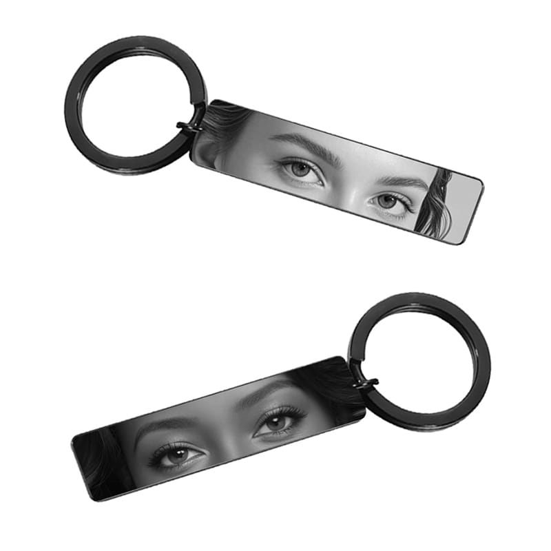 Black rectangular stainless steel keychain featuring a monochrome engraved portrait of eyes for custom personalization.