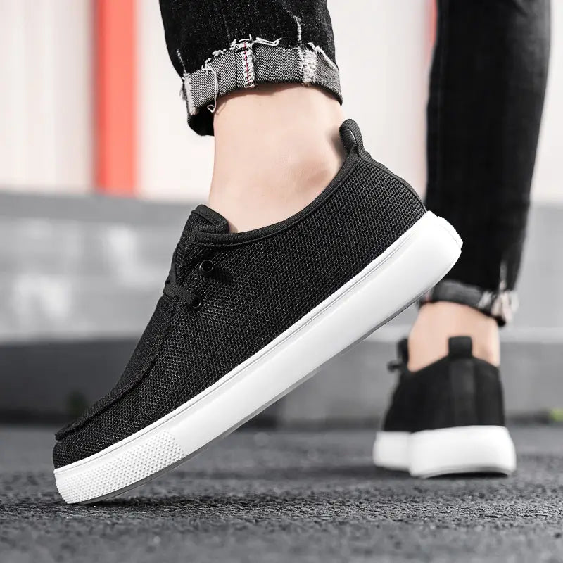 Chaussures de type mocassins décontractées pour hommes, baskets à enfiler en toile en maille noire, avec une semelle en caoutchouc blanc.