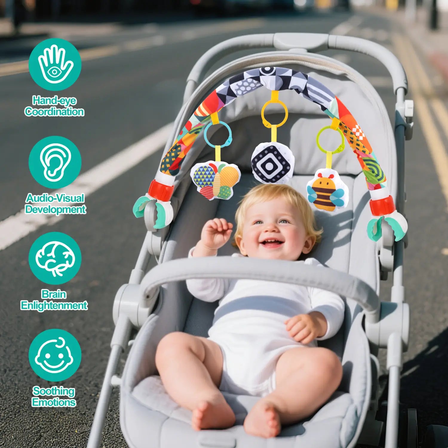 buntes Baby-Fahrwagenbogen-Spielzeug mit weicher, strukturierter Oberfläche aus gemustertem Stoff und baumelnden Spielzeugen für sensorische Förderung und Entwicklung im Säuglingsalter.