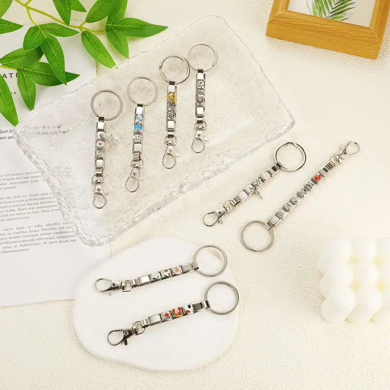 Llavero con dije de eslabones italianos personalizado en bricolaje, color plata, con una cadena con acabado plateado de eslabones metálicos entrelazados adornados con gemas de colores y pequeños dijes decorativos.