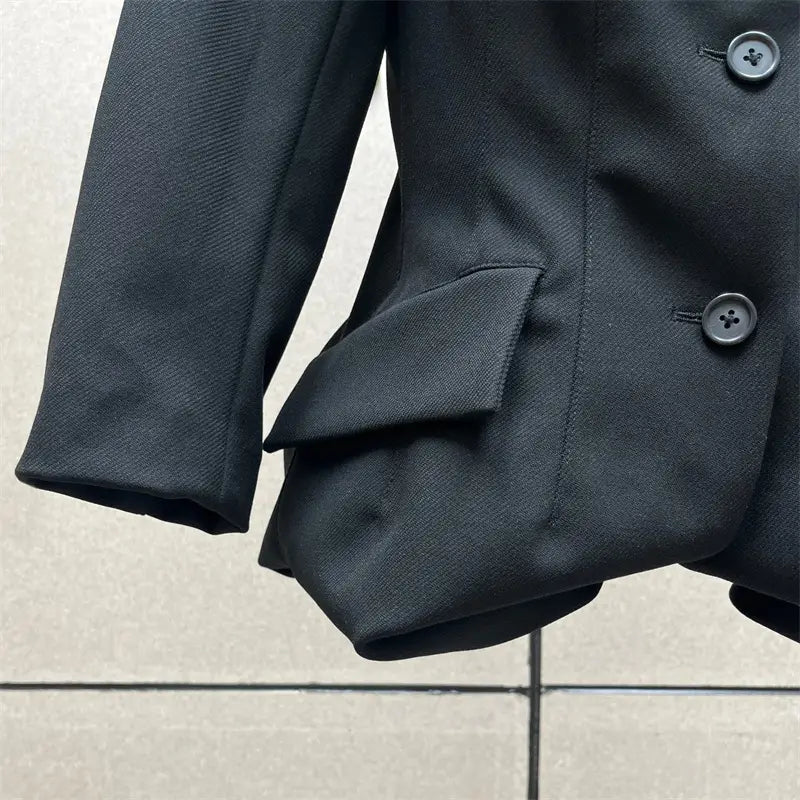 Blazer noir croisé à double boutonnage, tissu texturé et boutons assortis, associé à une jupe crayon grise taille haute Y2K de longueur genou.