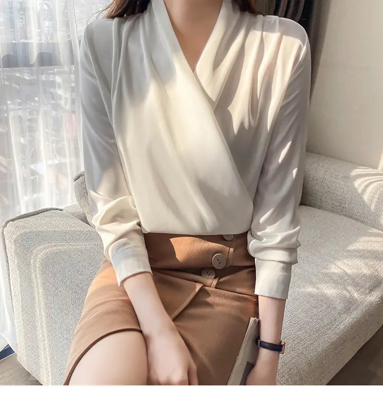 Vネックラインと長袖を備えた、やわらかなオフホワイトサテンのブラウス（女性用）。