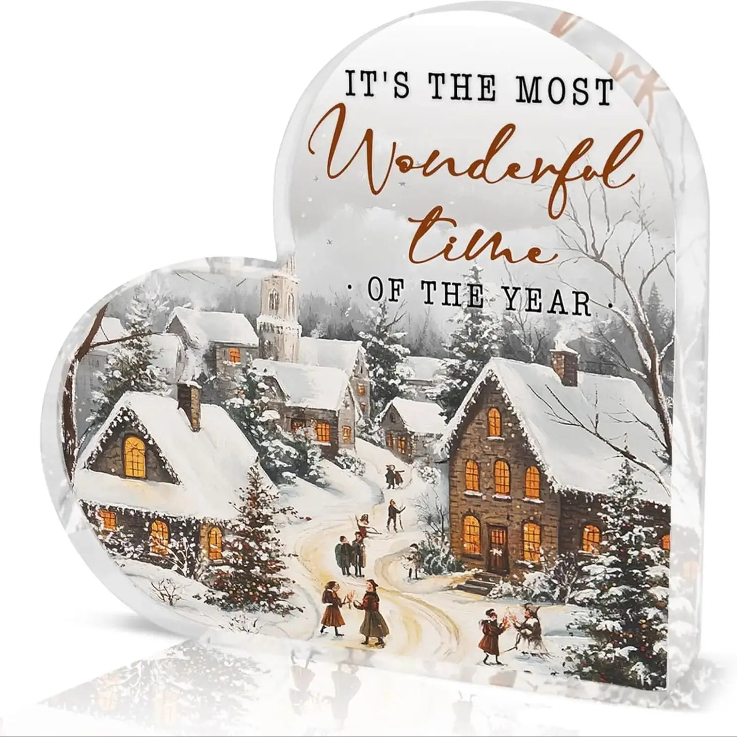 Décoration de table de Noël en acrylique en forme de cœur, comportant une plaque en forme de cœur avec une scène de village enneigé, des fenêtres illuminées et la phrase « its the most wonderful time of the year » dans une écriture élégante.