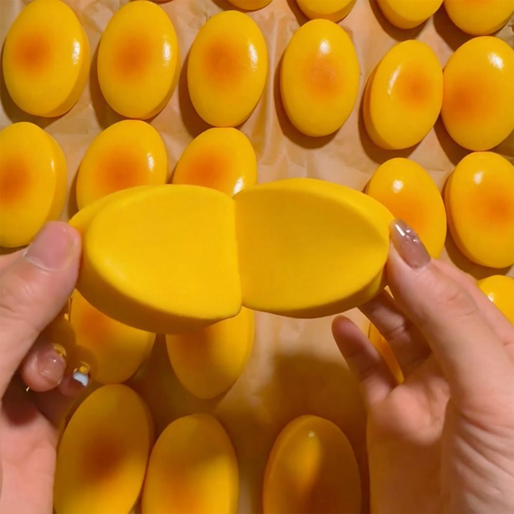 Juguete esponjoso para aliviar el estrés, en forma de óvalo, de color amarillo intenso, lento en elevarse, con una superficie lisa y brillante y un centro naranja sutil.