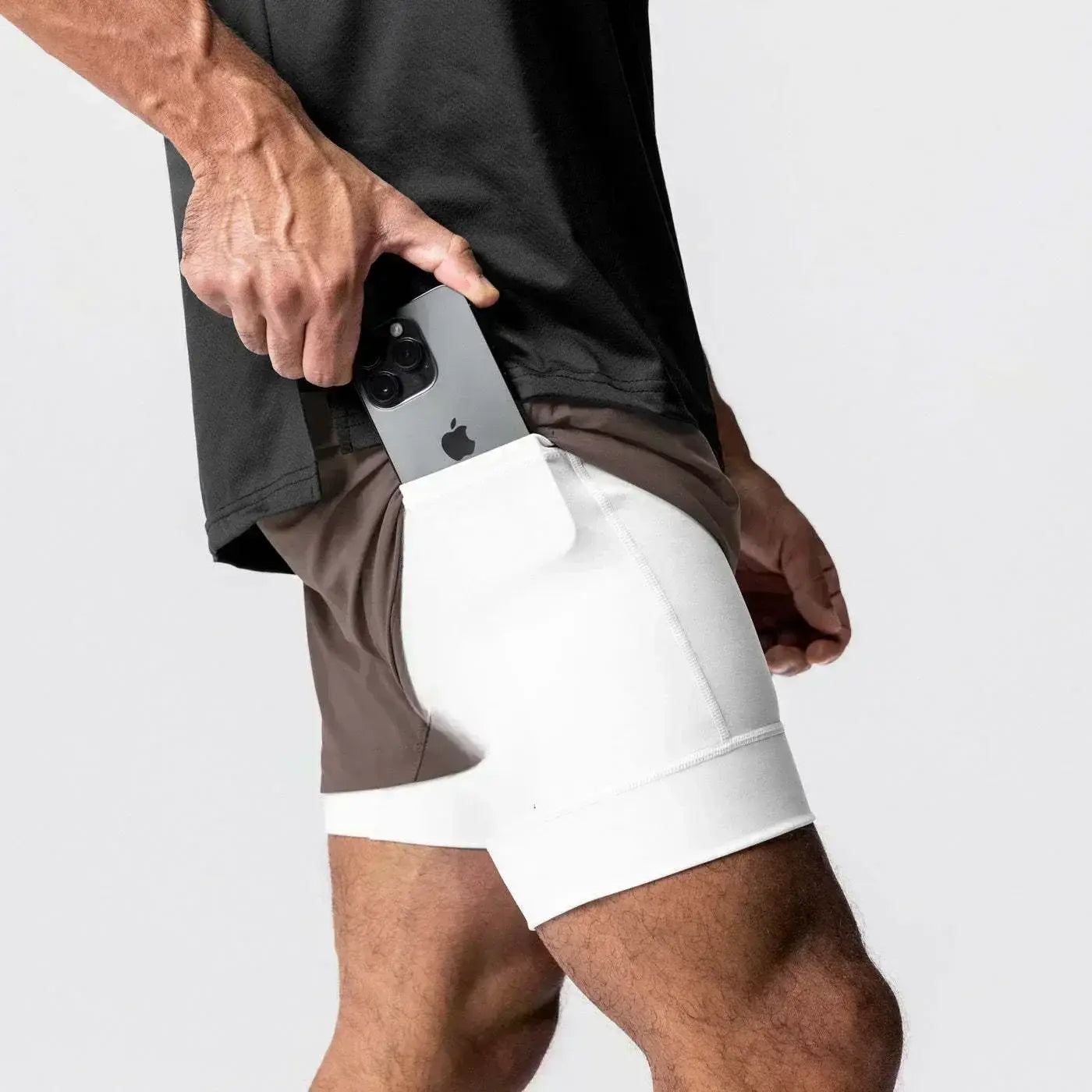 Hombres, pantalones cortos atléticos para gimnasio blancos con cintura elástica y trabilla para la toalla, que incluyen un bolsillo integrado para un teléfono inteligente.