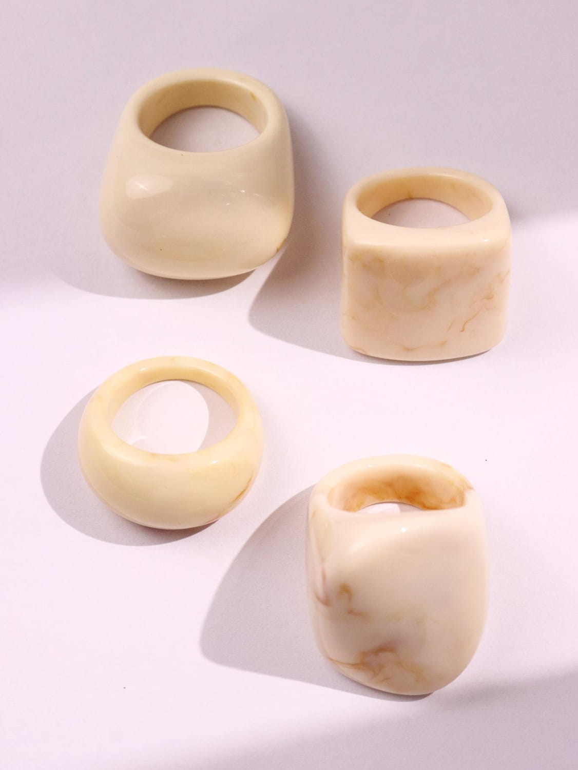 cream-colored chunky resin cocktail rings set with smooth surfaces and subtle marbled patterns in a 4-piece set