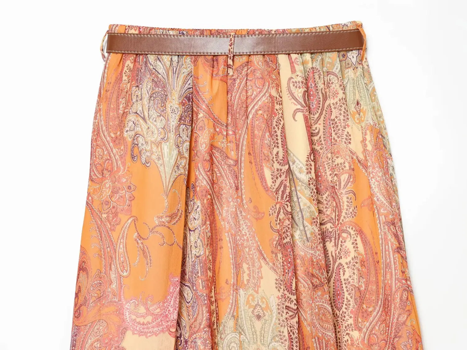 Jupe midi fluide à imprimé cachemire orange et beige, taille haute, avec une ceinture marron en cuir.
