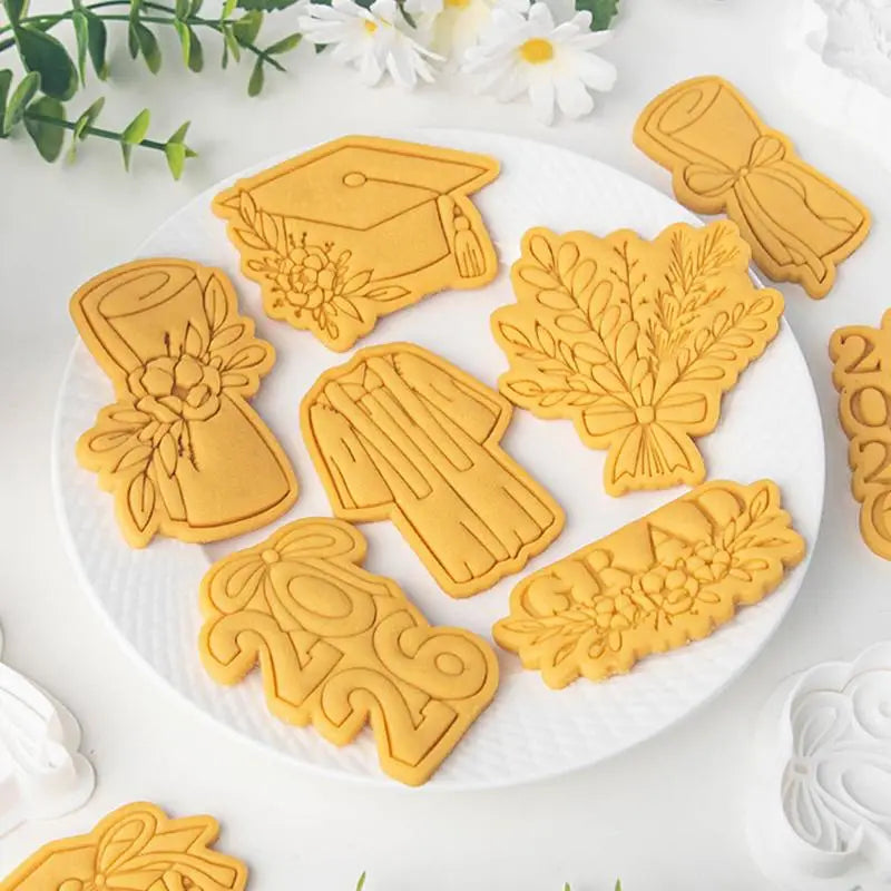 golden 2026 graduation cookie cutter set featuring shapes of caps gowns and floral arrangements for celebratory baking.