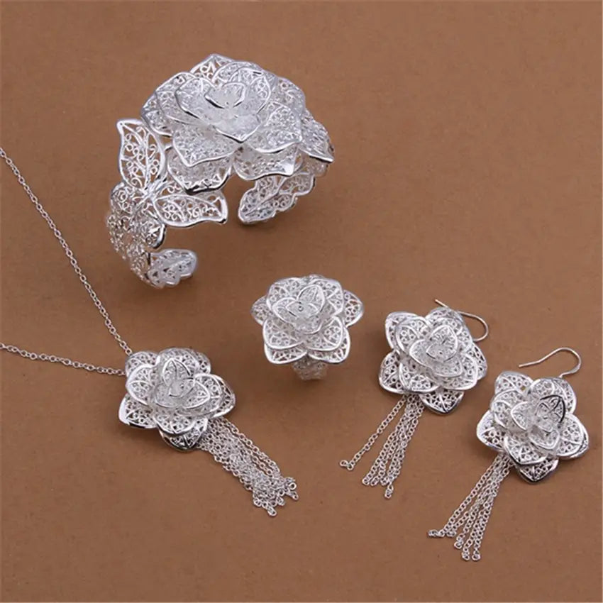 Parure de bijoux floraux en argent sterling, composée de bijoux floraux en argent présentant des motifs de filigrane complexes et des petits glands en chaîne délicats sur le pendentif et les boucles d’oreilles.