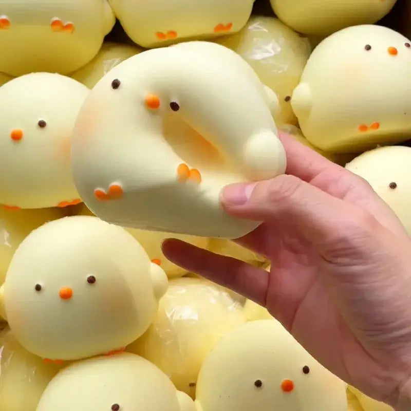 Un juguete blando tipo gallina gigante de color amarillo pálido con un pico y patas naranjas diminutos, mostrado desde el frente para aliviar el estrés.