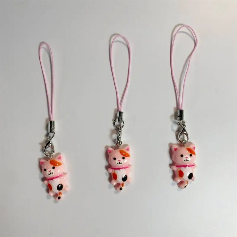 Pink plastic cat keychains with orange accents and pink fabric straps designed as cute cat phone charm straps.